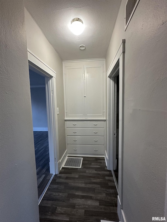 hallway featuring dark wood-type flooring and a textured ceiling