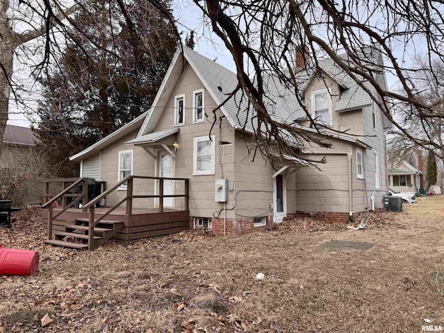 rear view of house featuring central AC unit and a garage