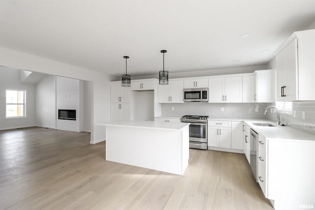 kitchen with stainless steel appliances, hanging light fixtures, sink, and white cabinets