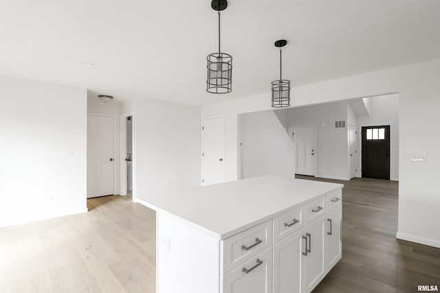 kitchen featuring white cabinetry, decorative light fixtures, a center island, and light wood-type flooring