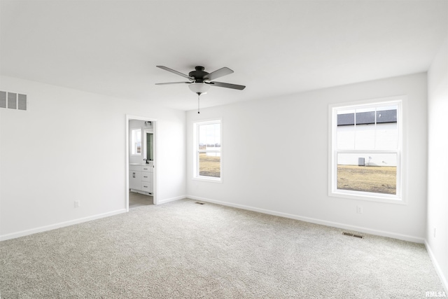 unfurnished bedroom featuring ensuite bathroom, light colored carpet, and ceiling fan