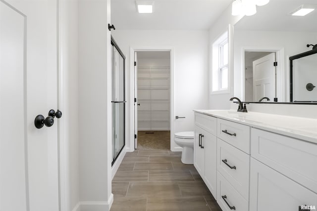 bathroom featuring vanity, toilet, and a shower with shower door