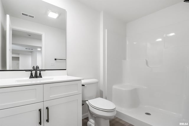 bathroom with vanity, hardwood / wood-style floors, a shower, and toilet