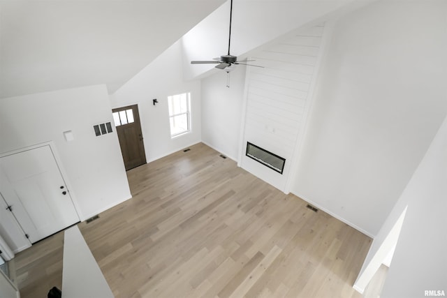 unfurnished living room featuring high vaulted ceiling, a fireplace, light hardwood / wood-style floors, and ceiling fan