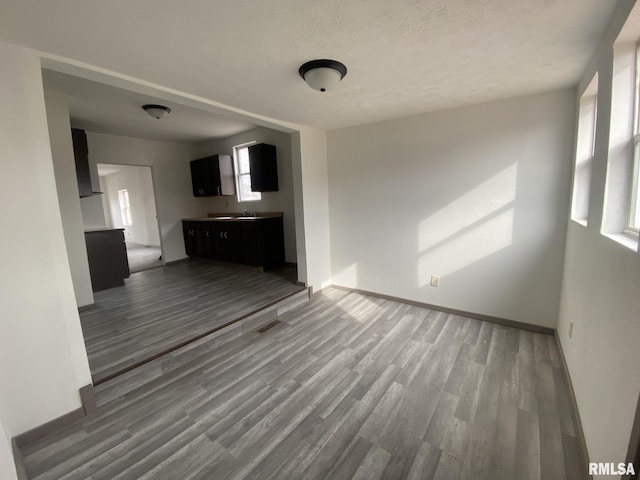 unfurnished living room featuring sink, a textured ceiling, and light wood-type flooring