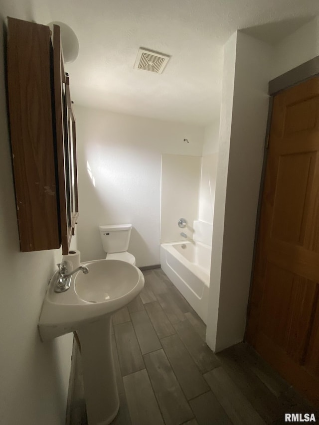 bathroom featuring a tub, hardwood / wood-style floors, and toilet