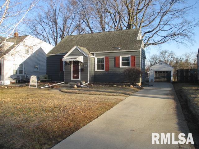 bungalow-style home featuring concrete driveway, a front lawn, an outdoor structure, and a detached garage