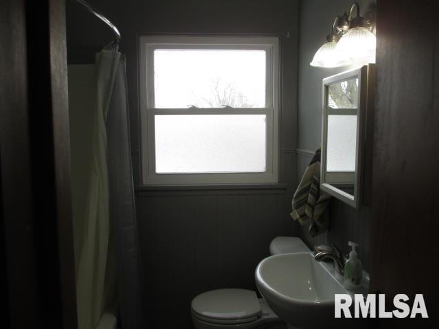 bathroom featuring a healthy amount of sunlight, toilet, curtained shower, and sink