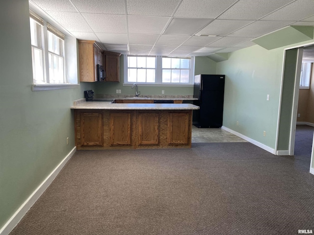 kitchen featuring a paneled ceiling, black appliances, sink, dark colored carpet, and kitchen peninsula