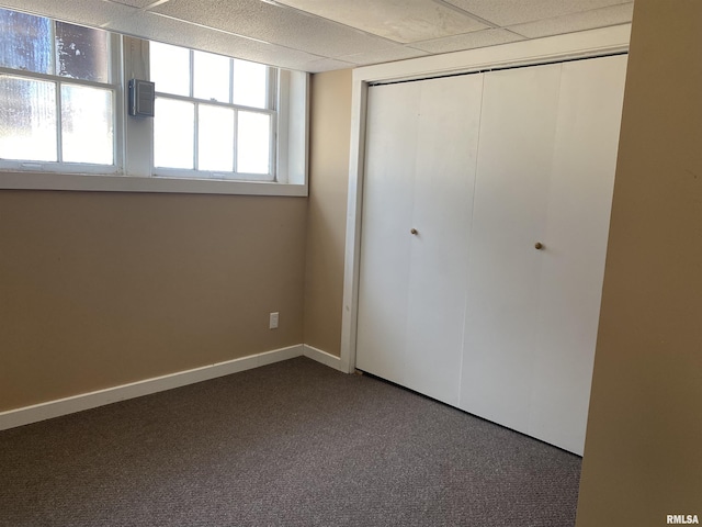 unfurnished bedroom featuring carpet floors, a paneled ceiling, and a closet