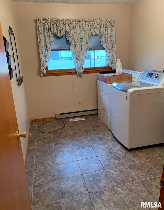 clothes washing area with a textured ceiling, washer and clothes dryer, and a baseboard radiator