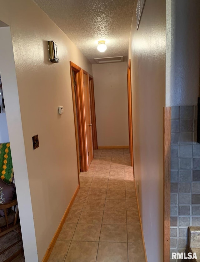 corridor featuring light tile patterned floors and a textured ceiling