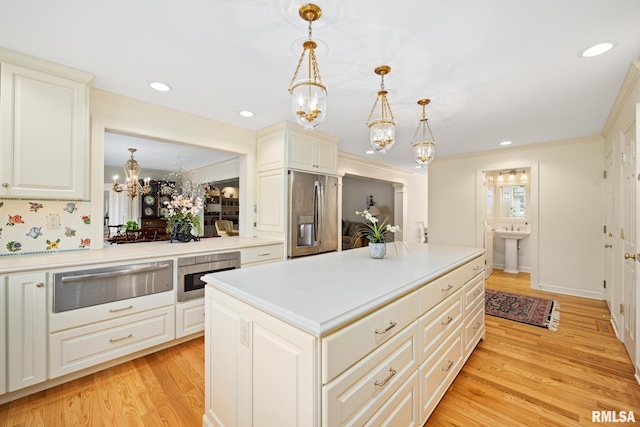 kitchen featuring pendant lighting, stainless steel appliances, ornamental molding, a kitchen island, and light wood-type flooring