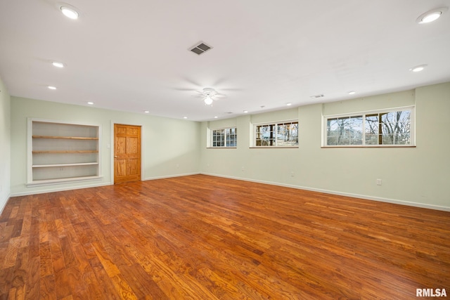 interior space with built in shelves, ceiling fan, a healthy amount of sunlight, and hardwood / wood-style floors