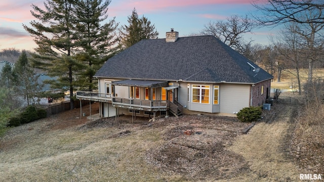 back house at dusk featuring a wooden deck