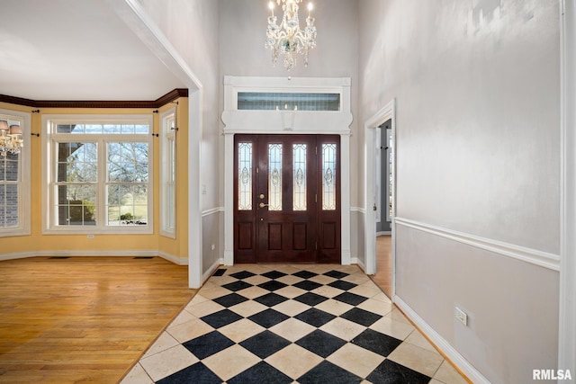 entrance foyer featuring a towering ceiling, a healthy amount of sunlight, and a notable chandelier