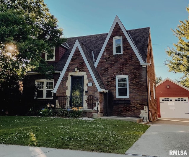 tudor home featuring a garage, an outbuilding, and a front lawn