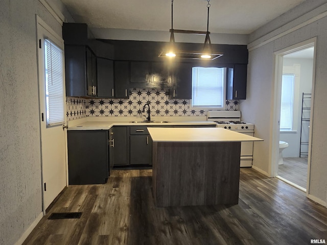 kitchen with dark hardwood / wood-style floors, decorative light fixtures, sink, a center island, and white range with gas stovetop