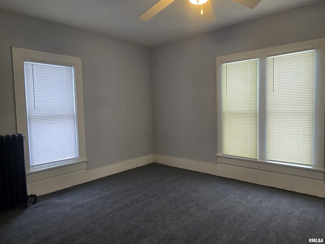 unfurnished room featuring dark carpet, radiator heating unit, and ceiling fan