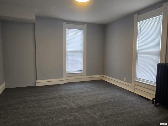 spare room with radiator and dark carpet