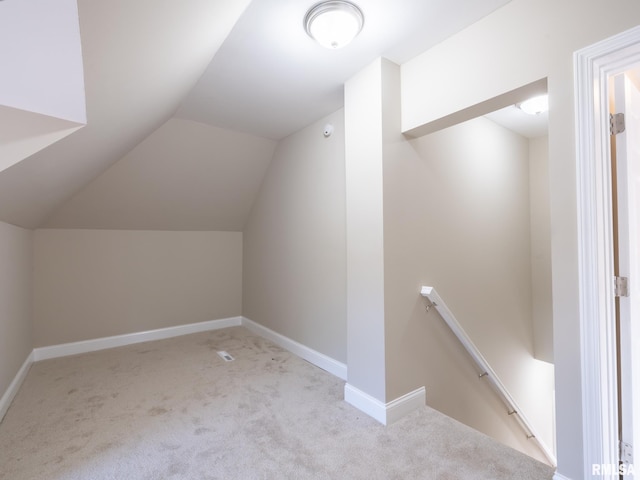 additional living space featuring lofted ceiling and light colored carpet