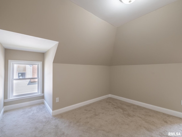 additional living space featuring light colored carpet and lofted ceiling