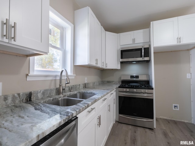 kitchen with light stone counters, sink, white cabinets, and appliances with stainless steel finishes