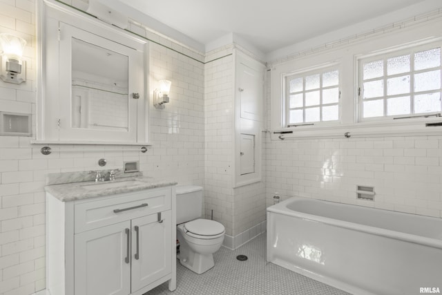 bathroom with vanity, tile patterned flooring, tile walls, and a tub