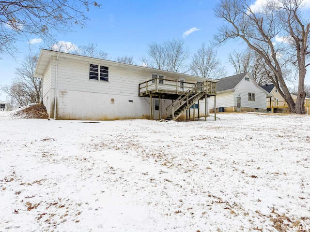 snow covered rear of property with stairway and a deck