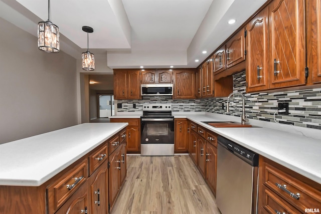 kitchen featuring sink, decorative light fixtures, light wood-type flooring, appliances with stainless steel finishes, and decorative backsplash