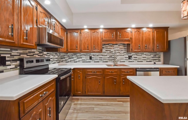 kitchen with appliances with stainless steel finishes, sink, light hardwood / wood-style floors, and decorative backsplash