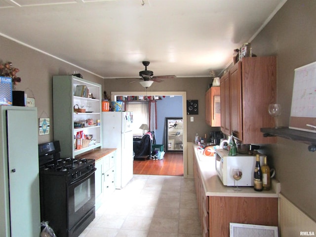 kitchen with white fridge, ceiling fan, and black gas stove