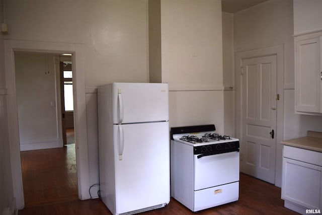 kitchen with dark wood-type flooring, white cabinets, and white appliances