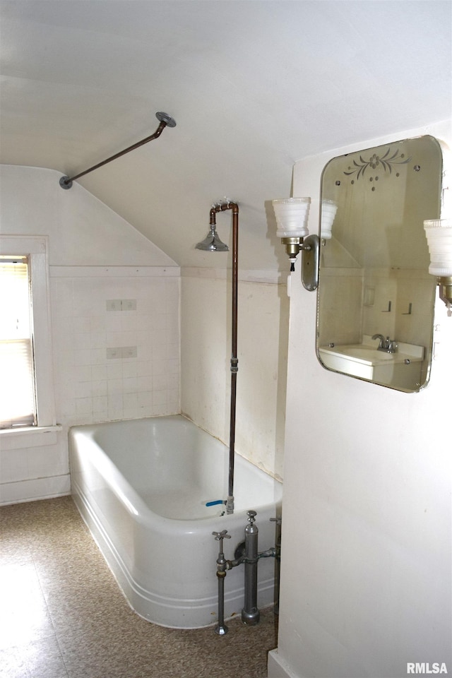 bathroom featuring lofted ceiling and a tub to relax in