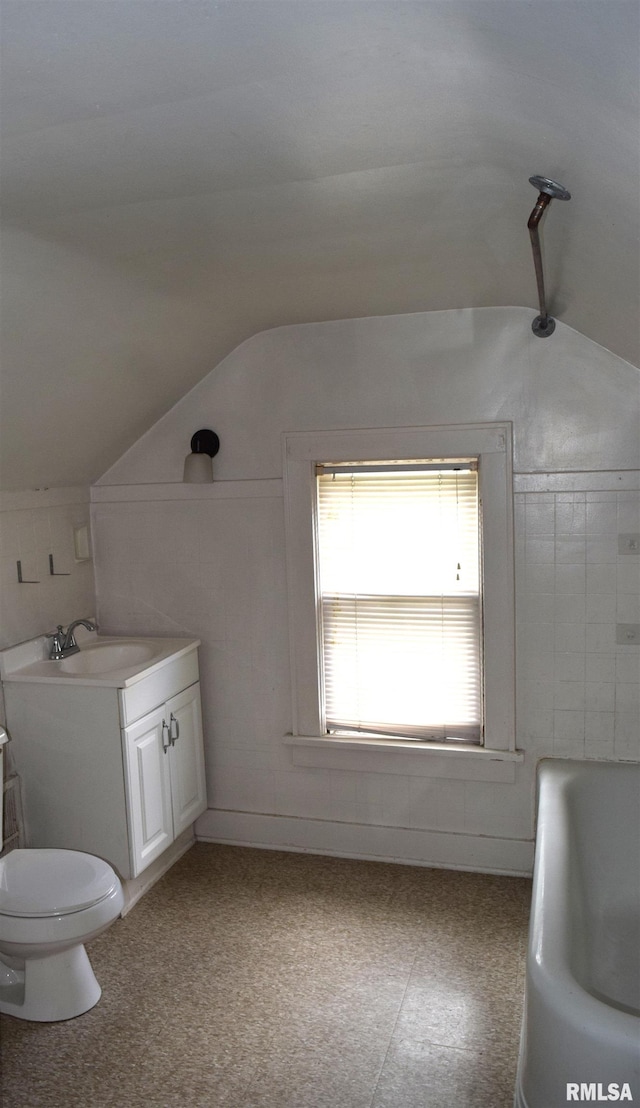 bathroom with vanity, toilet, a bathing tub, and vaulted ceiling