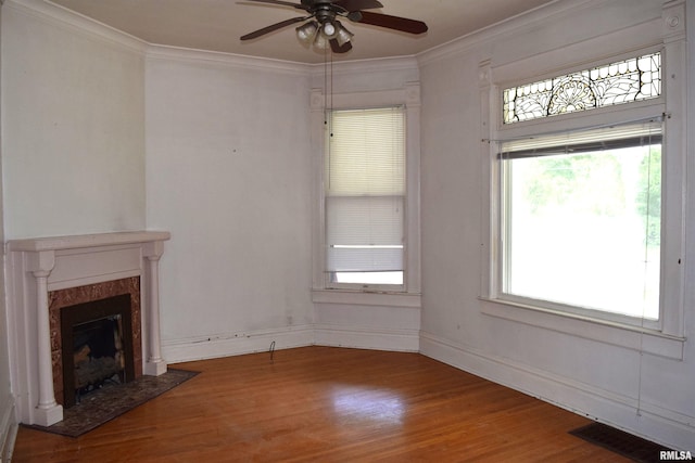 unfurnished living room featuring crown molding, ceiling fan, a premium fireplace, and hardwood / wood-style flooring