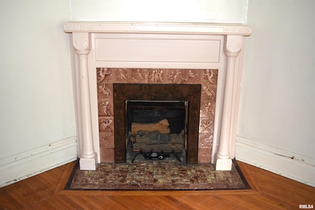 interior details featuring hardwood / wood-style flooring and a tiled fireplace