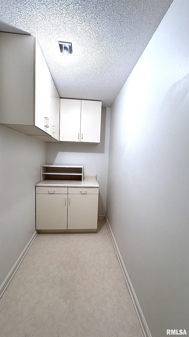 laundry room featuring light colored carpet, visible vents, a textured ceiling, and baseboards