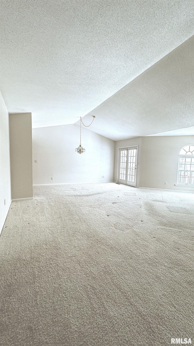 empty room with a healthy amount of sunlight, vaulted ceiling, and carpet flooring