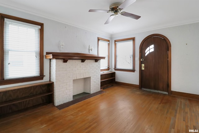 foyer featuring hardwood / wood-style floors, ceiling fan, crown molding, and a fireplace