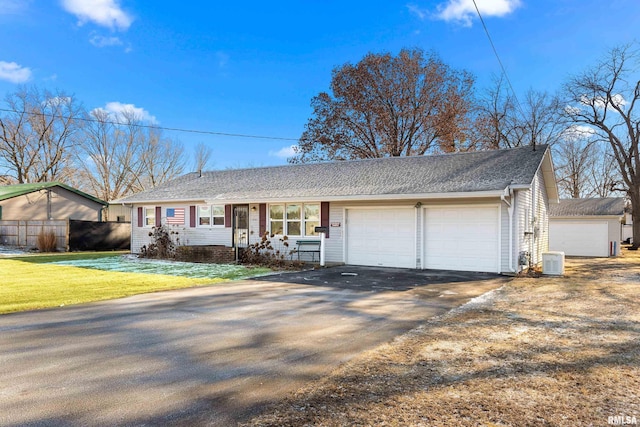 ranch-style home featuring a garage, a front lawn, and central air condition unit