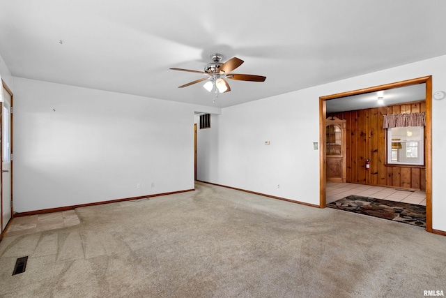 carpeted spare room featuring ceiling fan and wood walls