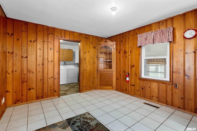 empty room with wooden walls, separate washer and dryer, and light tile patterned floors