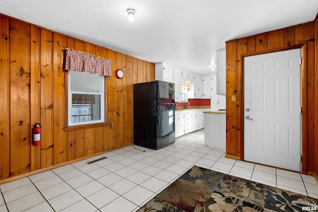 kitchen featuring white cabinetry, sink, black refrigerator, and light tile patterned flooring