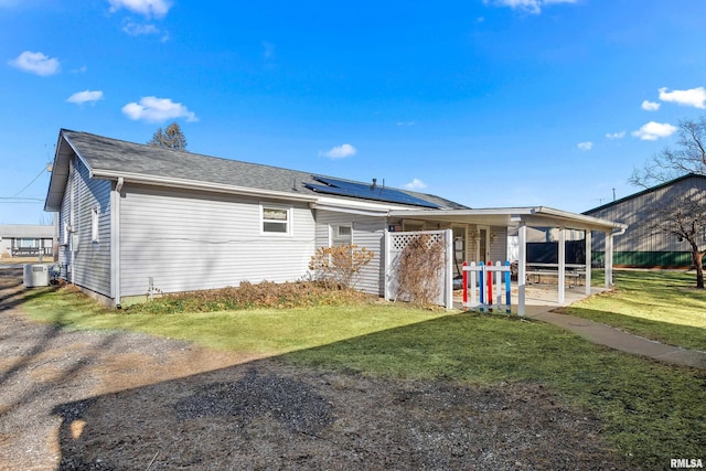 rear view of house featuring a lawn, central AC unit, and solar panels