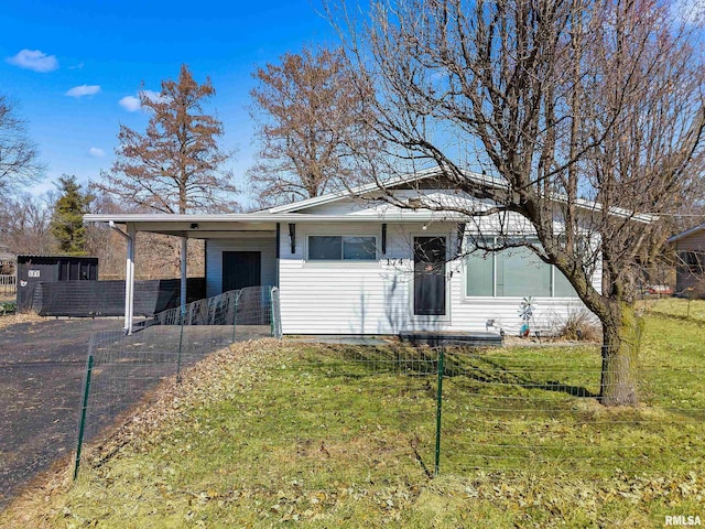 view of front facade with an attached carport, concrete driveway, fence, and a front yard