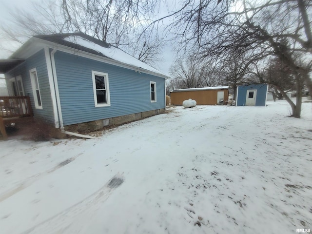 view of snowy exterior featuring a shed