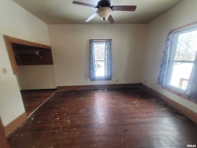 unfurnished bedroom with multiple windows, dark wood-type flooring, and ceiling fan