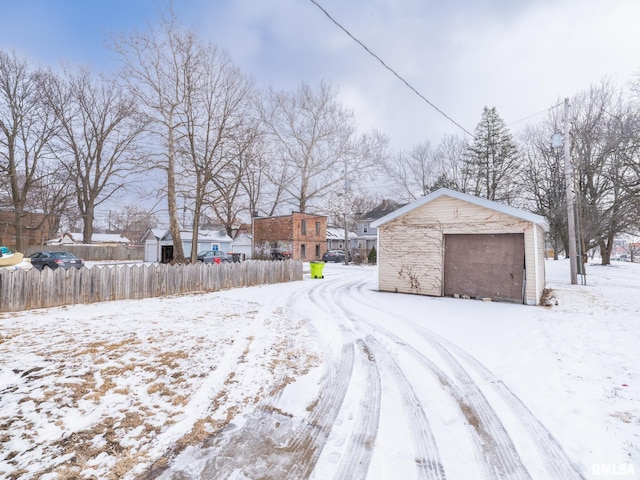 yard layered in snow with a garage and an outdoor structure