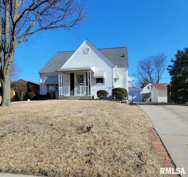 view of front of home with an outbuilding, roof with shingles, and a front lawn